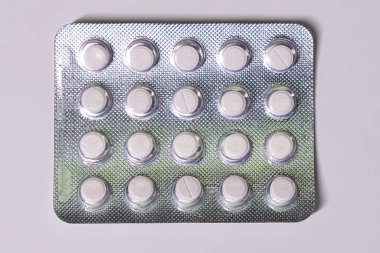 Dolu bir paket beyaz yuvarlak hap, gümüş destekli..