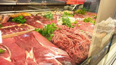 Kıyma, biftek ve diğer et kesimleri de dahil olmak üzere dondurulmuş kasaplarda sergilenen taze etin yakın plan görüntüsü..