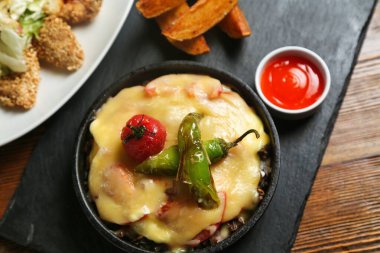 Yeşil biberli ve domatesli peynirli bir tabağın yakın çekimi acı soslu bir tabakta servis edilir..