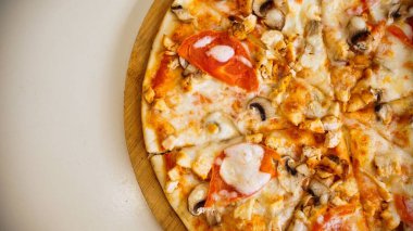 Erimiş peynir ve domates sosuyla kaplı tavuk ve mantarlı bir pizza..