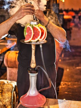 Adamın biri restoranda greyfurt kasesiyle nargile hazırlıyor..