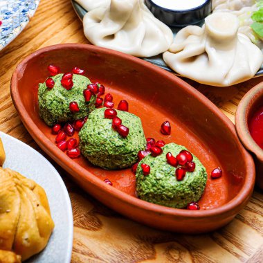 Üç porsiyon Gürcistan Pkhali 'sinin üzerine nar tohumu serpiştirilmiş hali. Yemek geleneksel bir kil tabakta servis edilir..