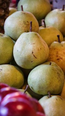 Bir market tezgahında üst üste yığılmış yeşil armutların yakın çekimi.