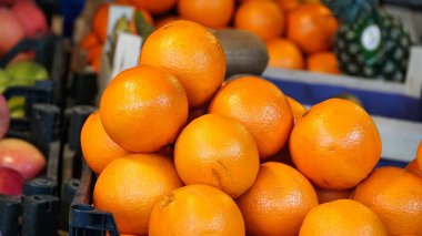 Bir market tezgahında plastik bir sandığa yerleştirilmiş taze portakal yığını..