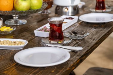 Bir bardak çay, bir tabak fındık ve beyaz bir tabakla ahşap bir masanın yakın plan çekimi..