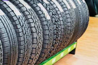 A close-up view of several new car tires displayed on a green shelf in a store. clipart