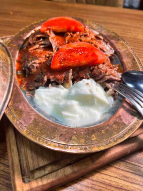 Bakır bir tabakta servis edilen yoğurt ve domates dilimli lezzetli bir Türk donör kebabının yakın çekimi..