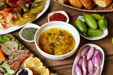 Turşu, soğan ve ekmek de dahil olmak üzere çeşitli mezeler içeren lezzetli bir Türk çorbası..