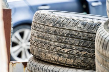 İki yıpranmış araba lastiğinin üst üste dizilmiş yakın plan çekimi, lastik izlerini ve yan duvarları gösteriyor..