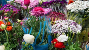 Plastiğe sarılıp bir markette sergilenen çeşitli renkli çiçek buketlerinin yakın plan görüntüsü.