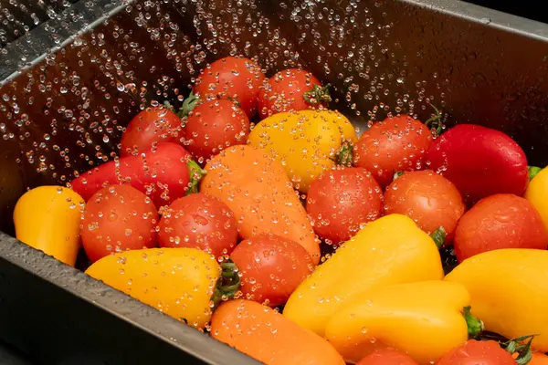 Renkli kiraz domatesleri ve mini dolma biberler lavaboda akan suyun altında durulanıyor, yemek yapmaya ya da servis yapmaya hazırlanıyorlar..