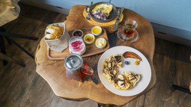 Eşsiz bir ahşap masada gözleme, yumurta, meyve ve içeceklerin sergilendiği canlı bir kahvaltı düzenlemesi..