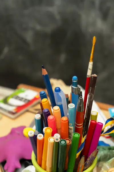 Canlı bir kalem, kalem ve kalem koleksiyonu masadaki bir kabı doldurur, sanatsal projeler ve yaratıcılık için mükemmel bir renk karışımı sunar..