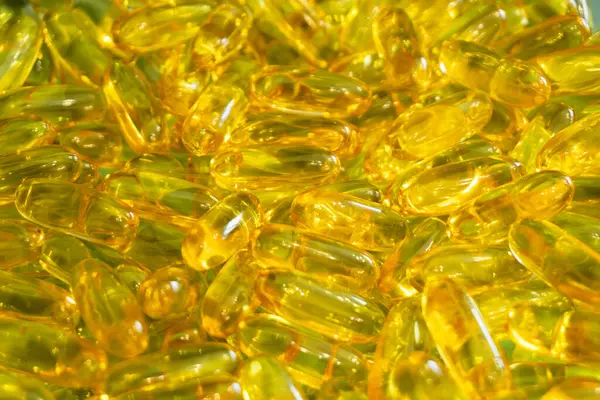 Parlak sarı jel kapsülleri bir araya toplanır, pürüzsüz yüzeylerini ve canlı renklerini doğal ışık altında göstererek dikkat çekerler..