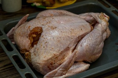 Bütün bir hindi bir fırın tepsisinde oturur, baharatlı ve kızartılmaya hazırdır. Dekor, bayramlarda aile yemeği hazırlığı yapılmasını öneriyor..