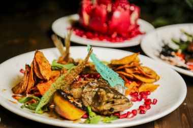 Çok güzel düzenlenmiş bir tabakta canlı otlar, patates cipsleri ve nar çekirdekleri ile süslenmiş balıklar, yaratıcı bir mutfak sunumunu ön plana çıkarıyor..