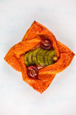 Lezzetli bir hamur işi, canlı meyve ve fındıkla dolu altın-kahverengi bir kabuk sergiliyor. Tatlı malzemeler bu hoşgörülü davranışa renk ve tat katıyor..