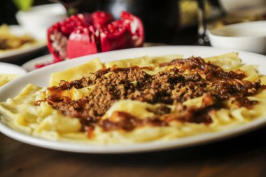 Lezzetli et sosuyla kaplı nefis bir tabak makarna. Etrafı renkli süslemeler ve canlı bir yemek setiyle çevrili..