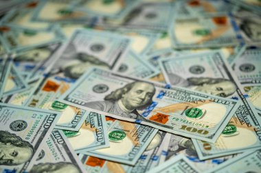 100 dolarlık banknotların bir koleksiyonu düz bir yüzeye yayılmış, karmaşık tasarımları ve paranın canlı renklerini detaylarıyla sergiliyor..