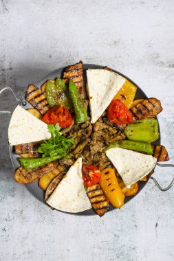 Canlı bir tabakta çan biberi ve domates gibi ızgara sebzelerin yanı sıra dilimlenmiş tortilla ve iyi baharatlı etin rengarenk bir yemek yaratması yer alıyor..