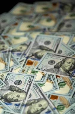 100 dolarlık banknotlardan oluşan bir kolleksiyon, ışığın yansımasını yansıtan karmaşık tasarım ve renkleri sergiliyor..