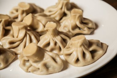 Yeni hazırlanmış hamur köfteleriyle dolu bir tabak yemek masasında oturup karmaşık kıvrımlarını ve pürüzsüz dokularını sergiliyor..