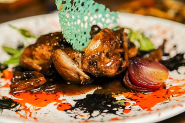 Güzel hazırlanmış bir bıldırcın tabağı renkli soslar, süslemeler ve kızarmış sebzelerle sunulur. Lüks bir yemek deneyimi için mükemmeldir..