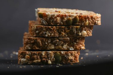 Yulaf, tohum ve fındıklardan yapılmış besleyici atıştırmalıklar karanlık bir yüzeye istiflenerek sağlıklı bir seçenek için dokularını ve sağlıklı malzemelerini sergiliyorlar..