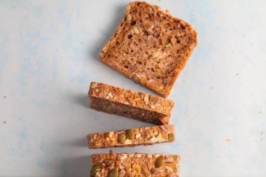 Tam tahıllı ekmek dilimlenir ve mavi bir yüzeye yerleştirilir, sağlıklı dokusunu ve ceviz malzemelerini vurgular, besleyici bir yemek veya atıştırmalık için mükemmeldir..