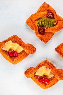 Hafif bir yüzeyde kiraz, ananas ve fındık da dahil olmak üzere çeşitli dolgulu taze pişmiş hamur işleri, dokularını ve renklerini gösteren estetik olarak düzenlenir..