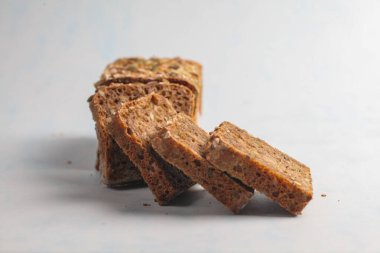 Taze pişmiş kahverengi ekmek açık bir yüzeyde oturur, birkaç dilim kesilir ve somuna yaslanır, dokusunu ve rengini gösterir..