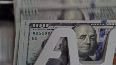 Yüzlerce dolarlık banknotların detaylı bir görüntüsü ve göze çarpan bir sergi standı. Nakit aranjmanı bir perakende ortamında değerini gösterir.