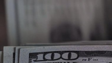 Yüz dolarlık banknotlar düzgünce düzenlenir ve karmaşık ayrıntıları gözler önüne serilir. Loş ışık, para birimine odaklanmış bir atmosfer yaratır..