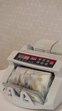Para sayma makinesi bir finans bürosu ortamında para yığınlarını verimli bir şekilde işler, para işleme görevleri için doğruluk ve hız sağlar. Dikey video.