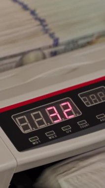 Bir para birimi sayma makinesi dijital ekranında toplam 83,2 dolar gösterir ve bu da bir finans kurumunda sayılan nakit miktarını gösterir. Dikey video.