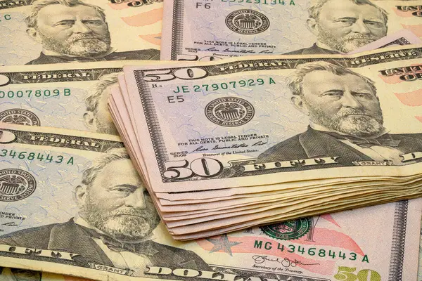 Elli dolarlık banknotlar düz bir zeminde düzenlenir ve karmaşık Amerikan para birimi tasarımlarını ve detaylarını iyi aydınlatılmış bir ortamda sergiler..