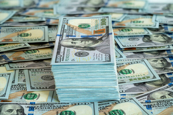 A bundle of hundred dollar bills rests prominently on a large spread of cash, highlighting wealth and financial abundance in a secure environment.