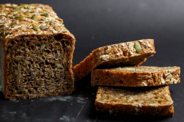Bu tam tahıllı ekmek somunu tohumlarla kaplı ve kalın parçalar halinde dilimlenmiş. Köy dokusu ve toprak renkleri sağlıklı bileşenleri vurgular..