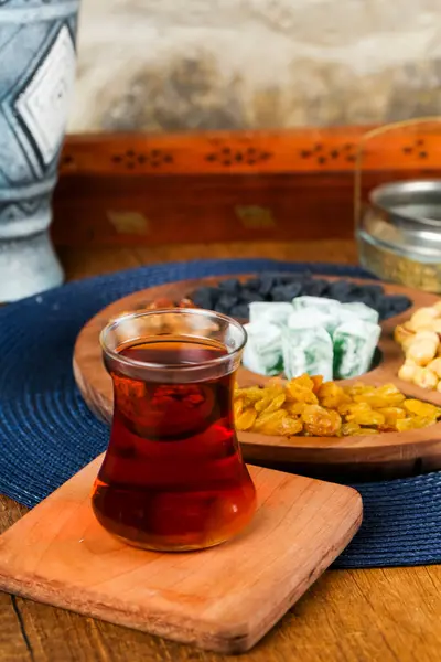 Bir bardak kehribar çayı, ahşap bir tepside çeşitli renkli atıştırmalıkların yanında durur. Paylaşmak için mükemmel bir ortam yaratır..