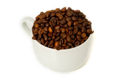 Beyaz bir fincan, zengin renkleri ve dokularını gösteren kızarmış kahve çekirdekleri ile dolup taşar. Basit bir arka plan fasulyelerin doğal güzelliğini vurgular..