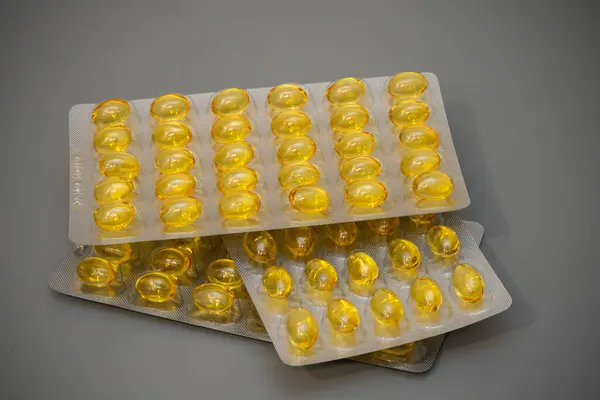 Sarı kapsüllerle dolu çoklu su toplayıcı paketler gri bir yüzeye düzgün bir şekilde yerleştirilmiş, takviyelerin yapılandırılmış düzenini ve canlı rengini vurguluyor..