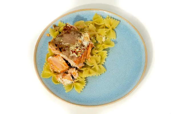 Canlı bir tabak, baharatlarla süslenmiş parlak yeşil papyonlu makarnanın yanında bol miktarda taze somon sunar..