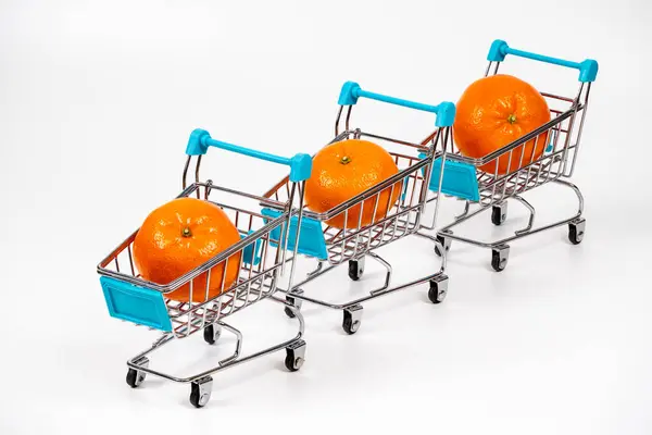 Minyatür alışveriş arabalarının her biri canlı bir portakala sahiptir, beyaz arka planda düzgün bir sıra halinde dizilmiş, market alışveriş temaları için idealdir.