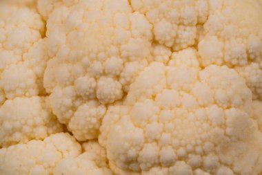 Benzersiz dokusunu ve kremsi rengini vurgulayan taze karnabaharın detaylı görüntüsü. Karmaşık desenler sebzenin doğal dizaynını ve tazeliğini gösteriyor..