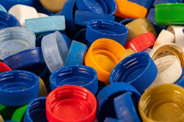 Geri dönüşüm çalışmaları için çeşitli boyutlarda ve renklerde sayısız canlı plastik şişe kapağı toplandı. Bu gruplama plastik atık yönetiminin önemini vurgular.