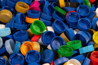 Şişe kapaklarının farklı renkte ve şekillerde canlı bir karışımı bir yüzeye yayılarak yaratıcılığı ve günlük ögelerde geri dönüşüm potansiyelini gösteriyor..