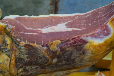 Bir satıcı İspanya 'daki bir markette büyük bir parça jambonu dikkatlice dilimliyor. Canlı atmosfer renk ve dokuların bir karışımını gösteriyor..