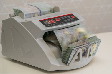 Para sayan bir makine, gündüz saatlerinde modern bir finans ofisinde nakit işleme verimliliğini yansıtan bir yığın banknot işliyor..