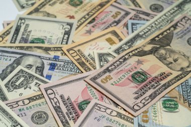 Düz bir zemine saçılmış çeşitli para birimleri koleksiyonu, finansal temalar için 20, 50 ve 100 dolarlık banknotlar sergileniyor..