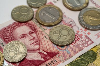 Çeşitli madeni paralar ve banknotlar farklı mezhepler, karmaşık tasarımlar, renkler ve tarihsel figürler, para biriminin çeşitliliğinin vurgulanması.